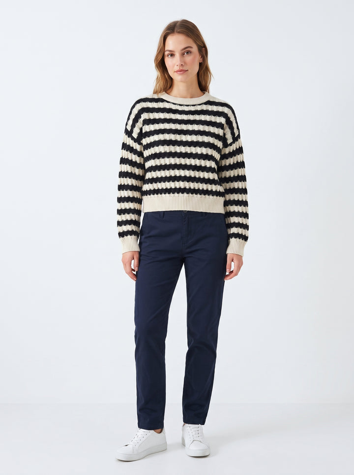 Studio photo of Suéter a rayas negro con beige manga larga Standing facing the camera, natural confident posture, arms relaxed at sides, front view, full body visible. CAMERA SHOT: A FULL BODY shot capturing the person from head to toe. [Full body]