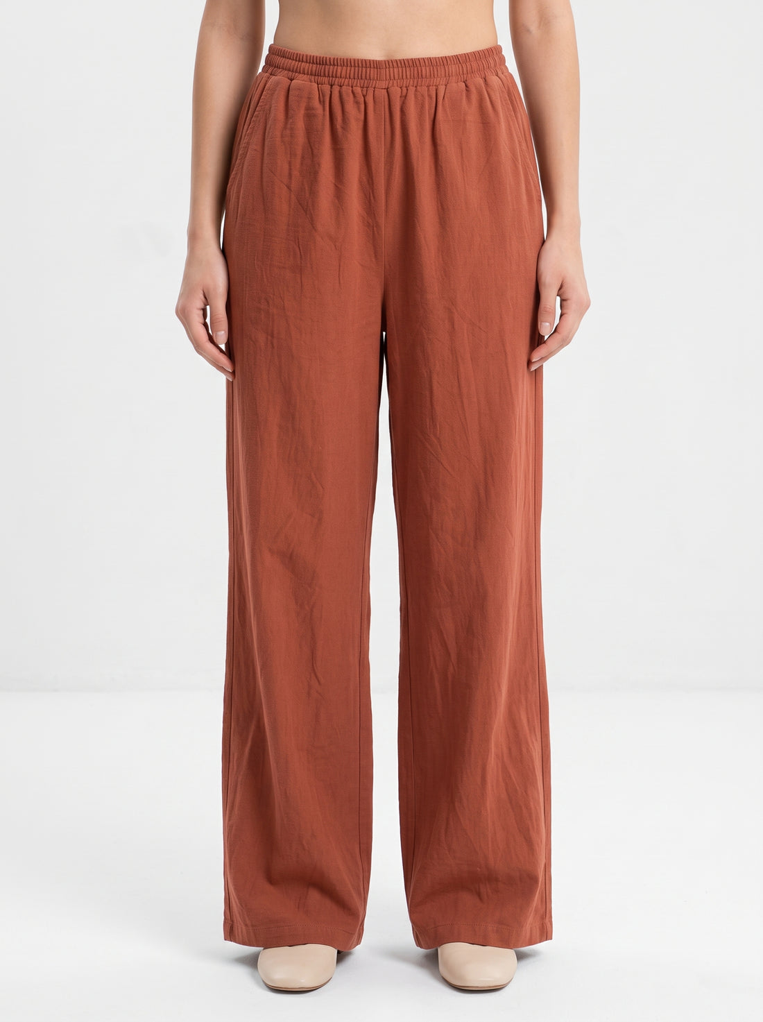 Studio photo of Pantalón rojizo Lower body shot from waist down, facing camera, showing pants/skirt front, legs straight. CAMERA SHOT: A FULL BODY shot capturing the person from head to toe. [Upper body focus]