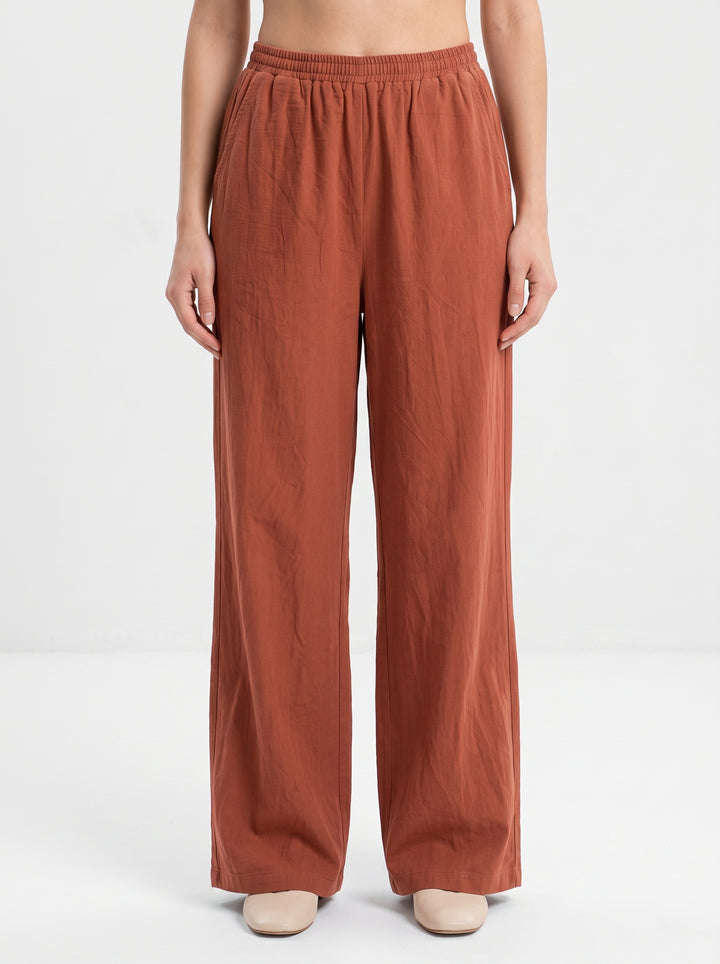 Studio photo of Pantalón rojizo Lower body shot from waist down, facing camera, showing pants/skirt front, legs straight. CAMERA SHOT: A FULL BODY shot capturing the person from head to toe. [Upper body focus]