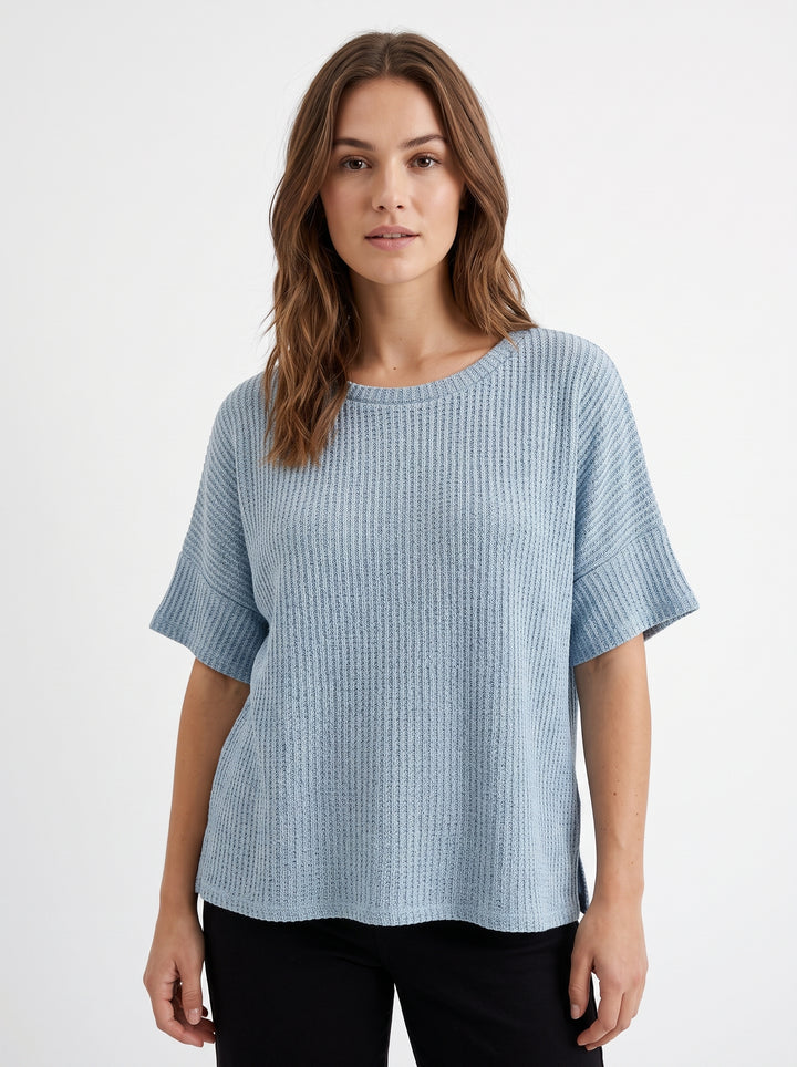 Studio photo of Blusa azul tejida Standing facing the camera, natural confident posture, arms relaxed at sides, front view, full body visible. CAMERA SHOT: A FULL BODY shot capturing the person from head to toe. [Upper body focus]