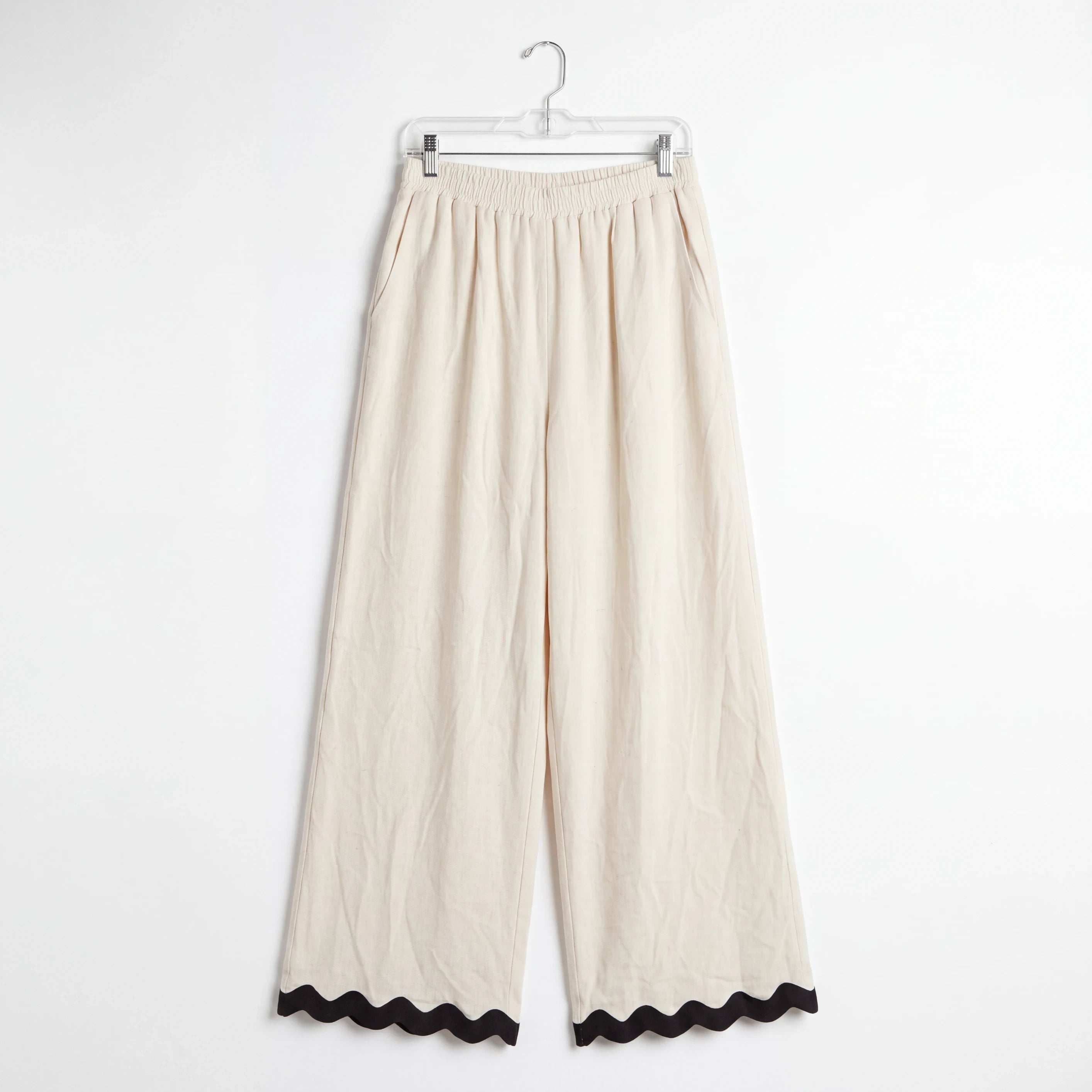 Pantalones wide-leg Yanet Collective beige con cintura elástica y detalle de ribete negro ondulado en el bajo