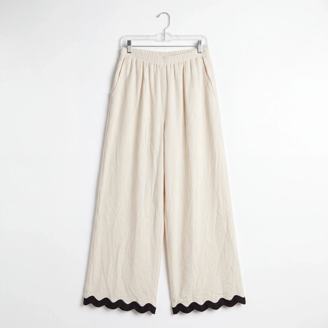 Pantalones wide-leg Yanet Collective beige con cintura elástica y detalle de ribete negro ondulado en el bajo