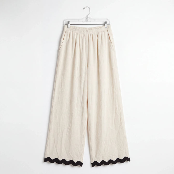 Pantalones wide-leg Yanet Collective beige con cintura elástica y detalle de ribete negro ondulado en el bajo